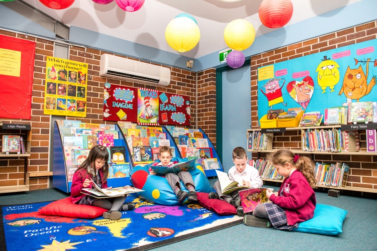 Four students sitting on beanbags reading books in a bright and colourful room