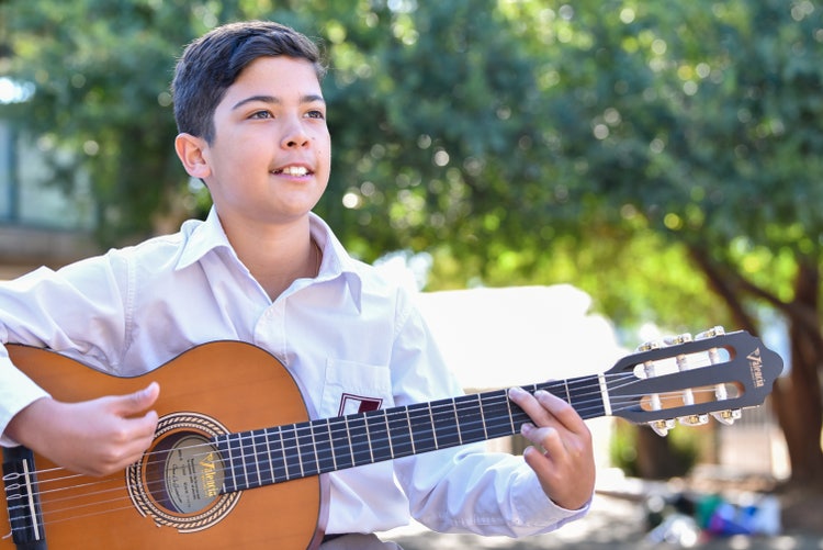 A student playing an acoustic guitar