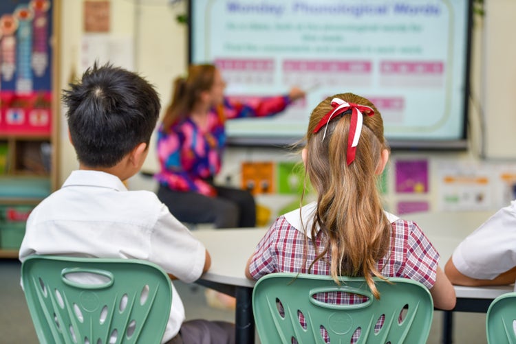 Two students reading from a smartboard in their classroom