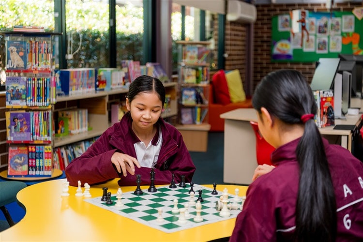 Two students playing chess in the library