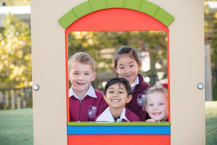 Four students smiling for a photo in the playground